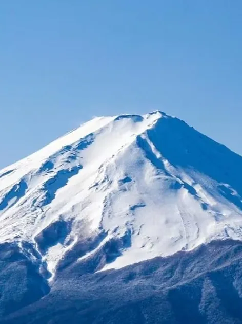 深い青空を背に、雪をかぶった富士山の山頂部