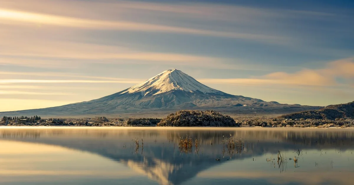 夕方の柔らかな光の中、静かな湖面に映る富士山