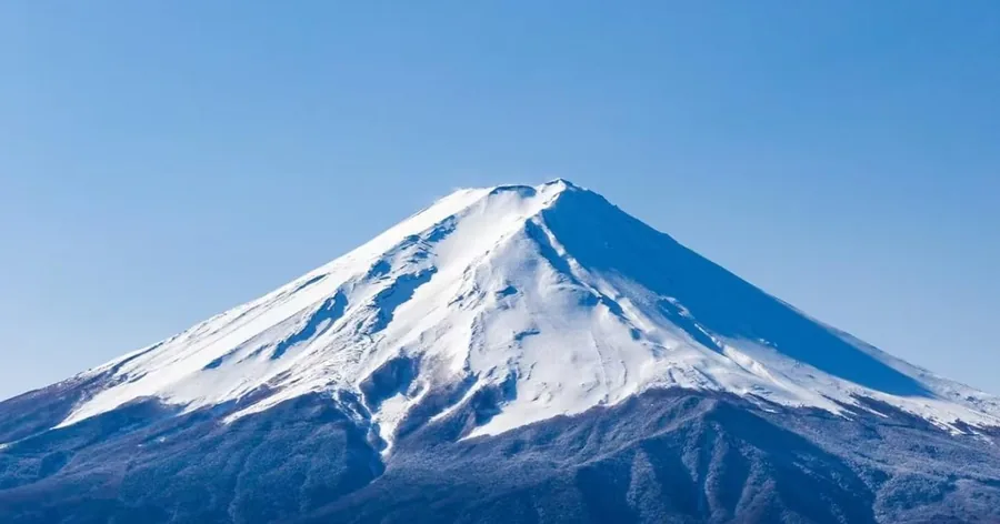 深い青空を背に、雪をかぶった富士山の山頂部